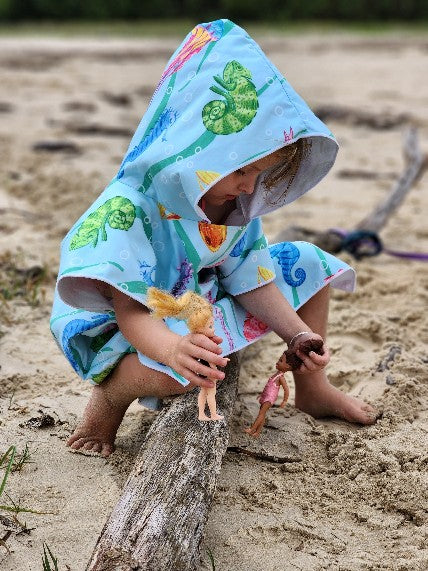 Young girl playing with her barbies on the beach with her Under the Sea sand less towel