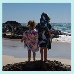 Boy and a girl standing on a rock in their sand free hooded towels Island Princess and Bird of Paradise